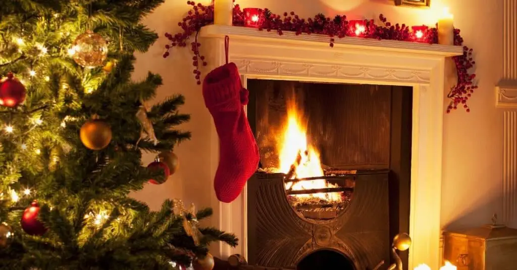 Stocking hung on lit fireplace next to a Christmas tree - Who is Kris Kringle - Open for Christmas
